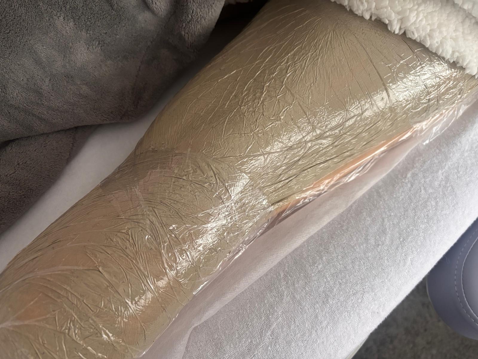 Een algenpakking tijdens de behandeling: het been in folie over de algen, op de behandelbank met witte handdoek